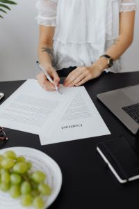 Kaboompics - Woman Signing Agreement Beside Laptop During Office Work