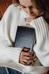 Kaboompics - Woman Resting Her Face on a Bible with a Cross Necklace