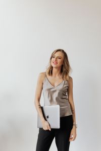 Kaboompics - Smiling Woman in Satin Blouse Holding a Laptop in Bright Studio