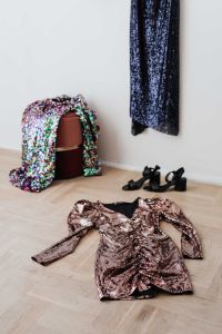 Kaboompics - colored sequin dresses and boots lie on a wooden parquet, blue dress hang on the white wall