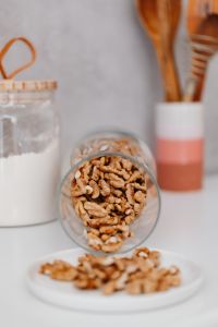 Kaboompics - Wooden Cooking Spoons in a Ceramic Holder with Walnuts and a Pantry Jar