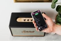 Kaboompics - Black speaker on marble table, white wall, mobile phone in hand