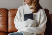 Kaboompics - Woman Holding a Holy Bible on a Brown Leather Sofa