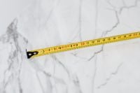 Kaboompics - Extended Yellow Measuring Tape Diagonally across White Marble, Minimal Renovation Texture