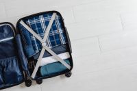 Kaboompics - Open Suitcase with Folded Clothes and Wide White Tile Copy Space