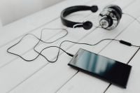 Kaboompics - Black Smartphone and Wired Headset with Tangled Cord on White Planks