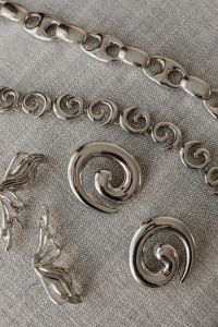 Kaboompics - Silver Spiral Earrings and Chains on a Sofa