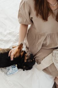 Kaboompics - Pregnant Woman Petting Small Dog Beside Baby Shoes