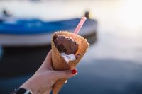 Kaboompics - Close-Up Chocolate Ice Cream Cone with Blurred Blue Boat Background