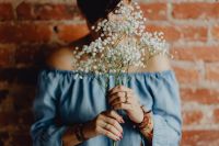 Kaboompics - A woman in a blue dress holds a branch of Baby's Breath flower