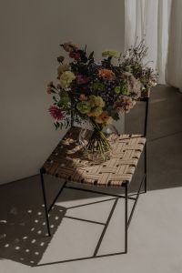 Kaboompics - Dark Ceramic Vase with Colorful Bouquet on Woven Chair