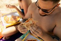 Kaboompics - Smiling Woman Enjoying Pizza During a Beach Lunch