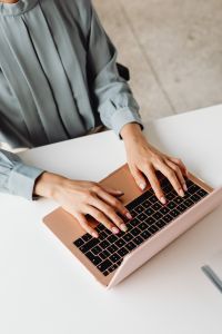 Kaboompics - Close-Up of Hands Typing on a Pink Laptop at a Desk