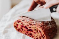 Kaboompics - Hand Cutting Beetroot Bread Loaf on Linen