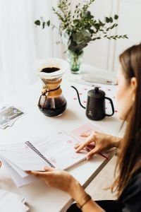 Kaboompics - Woman Reviewing Her Notebook Beside Chemex Coffee at Home Office