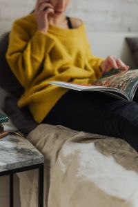 Kaboompics - Woman Browsing an Open Magazine on a Sofa, Cozy Reading Break