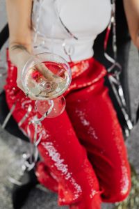 Kaboompics - Woman in red pants and a white shirt is sitting on a chair with glass