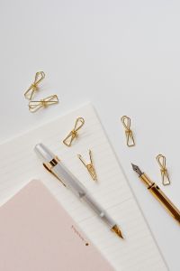 Kaboompics - Two Fountain Pens, Gold Clips and Pink Notepad on Lined Paper, Vertical Office Supplies Photo