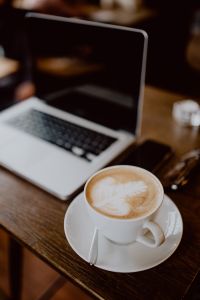 Kaboompics - Cup of coffee & MacBook laptop on table in cafe