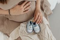 Kaboompics - Expecting Mother Resting Hands on Baby Bump with Blue Baby Shoes