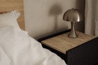 Kaboompics - Close-Up of Metallic Table Lamp on Textured Nightstand beside White Bed