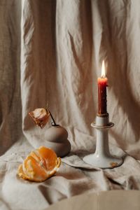 Kaboompics - Lit Red Taper Candle With Mandarin And Dried Rose On Linen