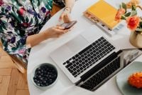 Kaboompics - Top View of Woman Using a Smartphone at a Laptop Workspace