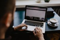 Kaboompics - Man Working on Laptop beside a Striped Cappuccino at a Dark Desk