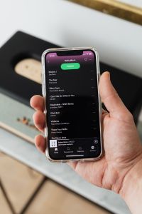 Kaboompics - Black speaker on marble table, white wall, mobile phone in hand