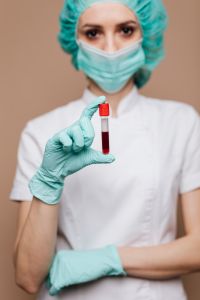 Kaboompics - Masked Healthcare Worker Pointing to a Blood Sample Tube, Vertical Medical Testing Portrait