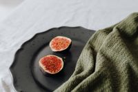 Kaboompics - Halved Figs on Speckled Black Stoneware with Olive Knit, Moody Fruit Styling for Recipe Design