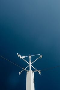 Cardinal Direction Wind Vanes: Rooftop Navigation Signs Against a Clear Blue Sky