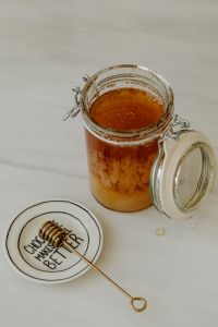 Kaboompics - Honey Jar and Wooden Dipper on Lettered Plate, Minimal Kitchen Food Styling with Copy Space