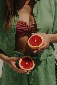 Kaboompics - Woman Holding Grapefruit Halves in a Pink Swimsuit and Green Cover-Up