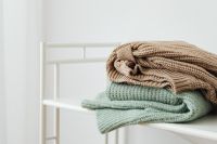 Kaboompics - Folded Sage and Beige Sweaters on a Shelf