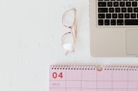 Kaboompics - Pink Desk Calendar, Glasses and Laptop Keyboard for Workspace Planning