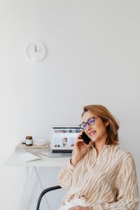 Kaboompics - Smiling Woman Talking on Smartphone with Home Office Copy Space