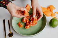 Kaboompics - A woman peels an orange on a green plate