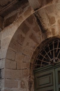 Kaboompics - Aged Stone Arch and Ornate Window Grille on Historic Facade