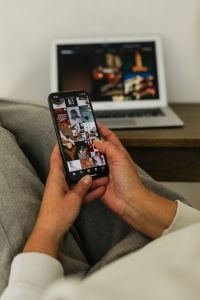 Kaboompics - Close-Up of Instagram Feed on Smartphone With Laptop Background