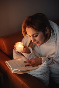 Kaboompics - Woman Reading Under a Blanket with a Candle at Home