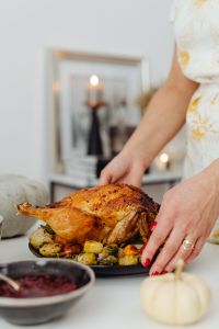 Kaboompics - Hands Setting Roast Turkey with Vegetables on Festive Table