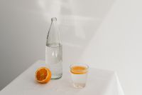 Kaboompics - Minimal Orange Water Still Life with Bottle and Citrus Glass, White Background with Copy Space