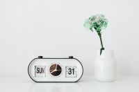 Kaboompics - White Retro Flip Calendar Alarm Clock Beside a Mint-Green Flower in a Ceramic Vase