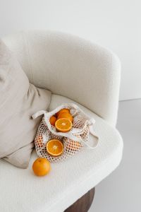 Kaboompics - Halved Oranges and a Reusable Produce Bag on Textured Cream Upholstery