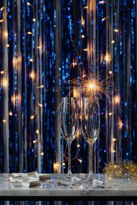Kaboompics - Close-Up Golden Sparkler Over Champagne Glasses with Festive Blue Tinsel