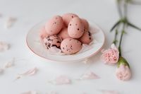 Kaboompics - Pink Speckled Chocolate Easter Eggs on a White Plate with Spring Blossoms and Petals