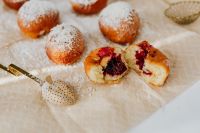 Kaboompics - Traditional Polish Paczki with Dark Cherry Filling and a Gold Pastry Strainer on Linen