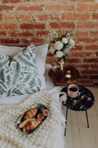 Kaboompics - Croissant and Fig Breakfast on a Textured Knit Bed, Coffee and Floral Decor on a Marble Side Table