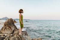 Kaboompics - Woman in a Green Dress Standing Side-On on Coastal Rocks, Open Sea and Summer Travel Copy Space
